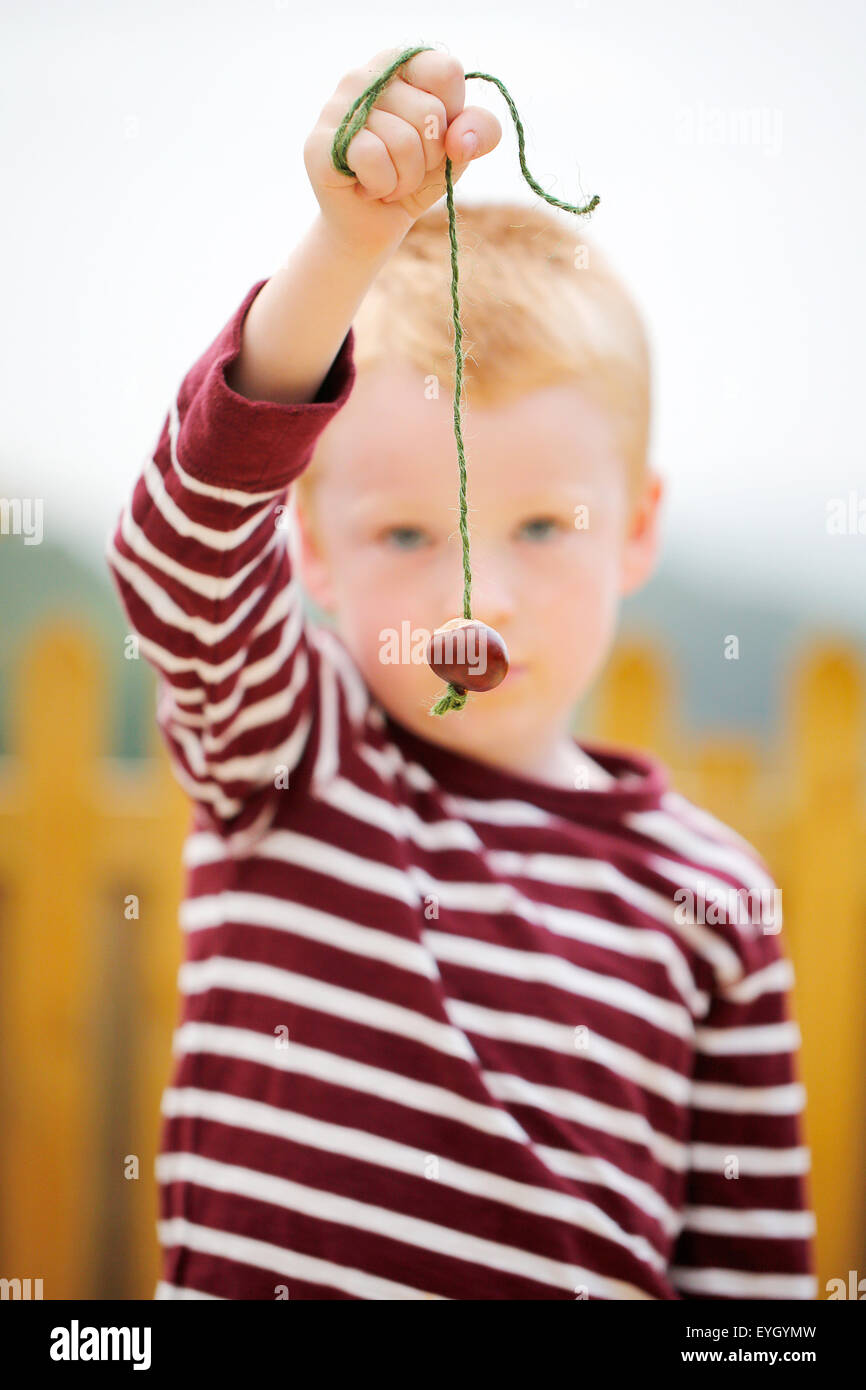 Un jeune garçon tenant un conker sur une chaîne. En attendant de participer à un jeu à l'ancienne de l'anglais conkers Banque D'Images