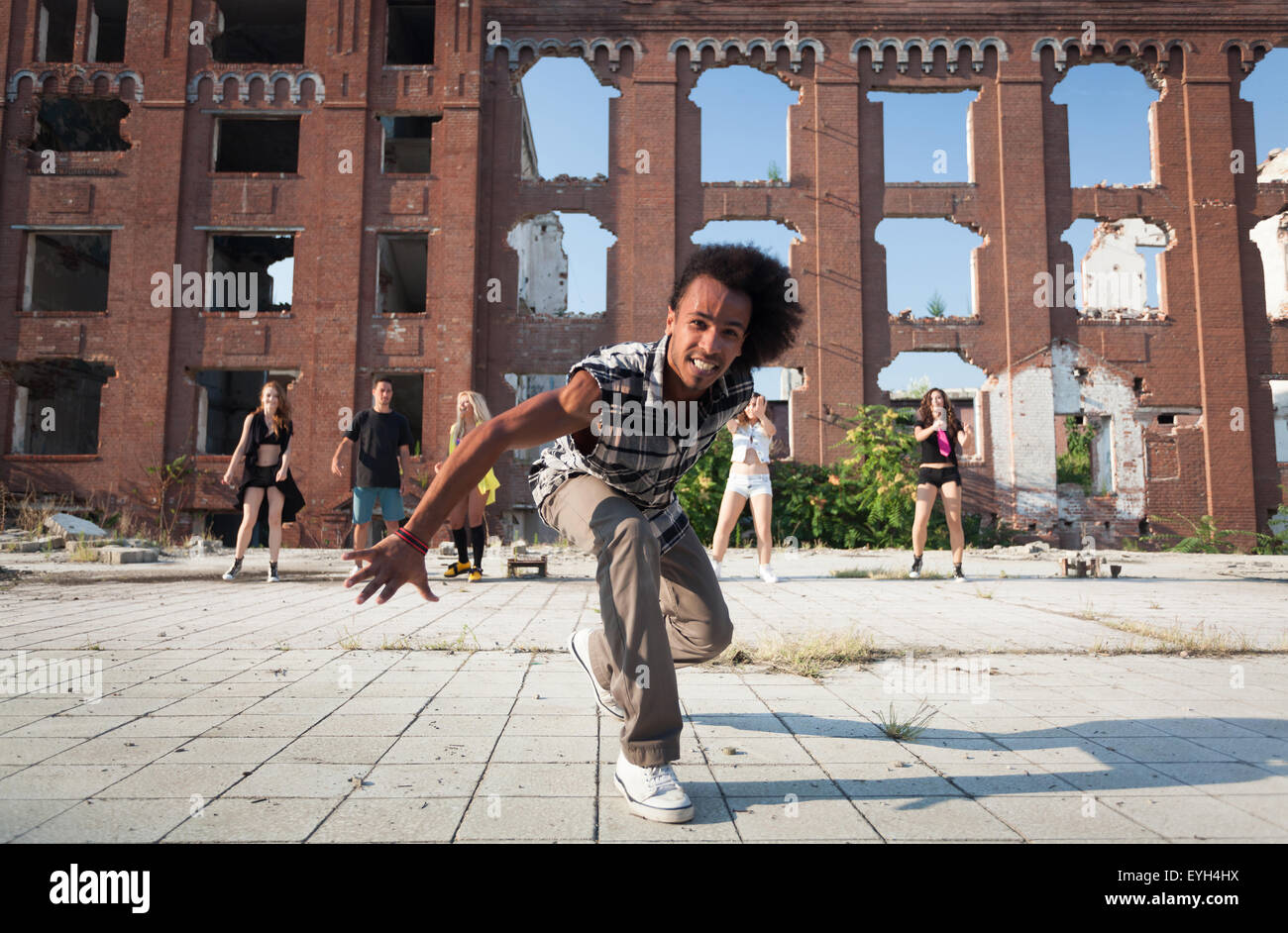 Heureux de l'Afrique de l'énergique American street dancer se précipitant sur l'appareil photo avec un sourire espiègle qu'il effectue sa danse hip hop routin Banque D'Images