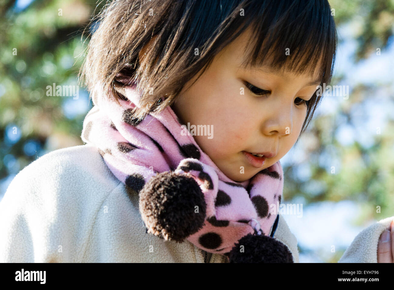 Close up of vue latérale du visage de jeune fille japonaise tout en regardant vers le bas à l'extérieur. Enfant, 4-5 ans. Porte manteau d'hiver gris et écharpe rose. Banque D'Images