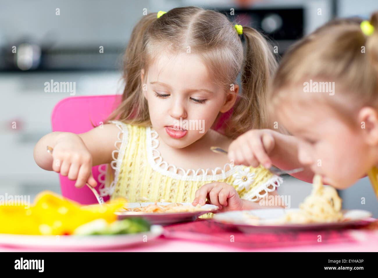 Les enfants mange du spaghetti avec des légumes dans les jardins Banque D'Images