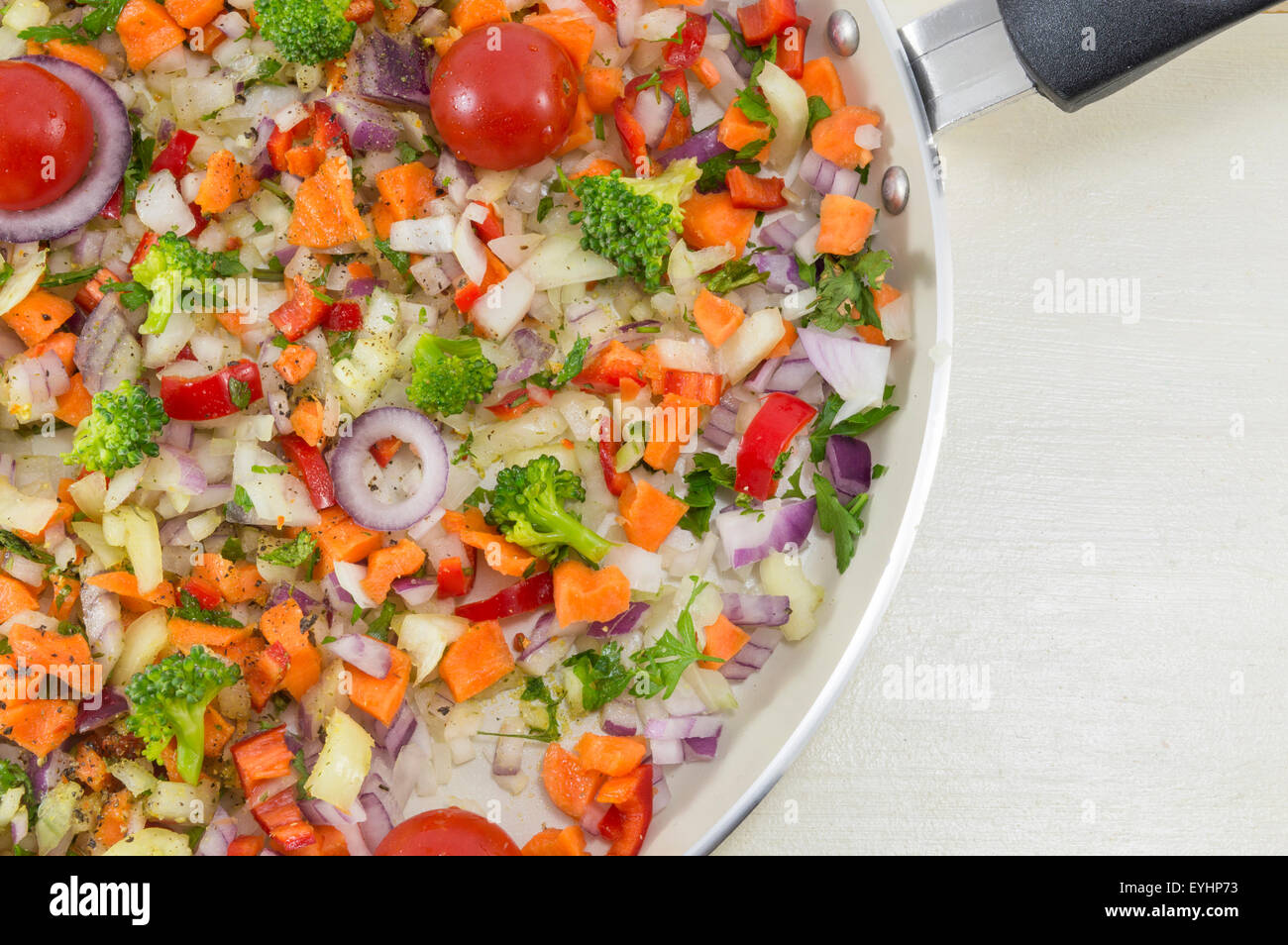 Salade de légumes sur une casserole prêts à être cuisinés pour un repas santé mis sur la table en bois blanc Banque D'Images