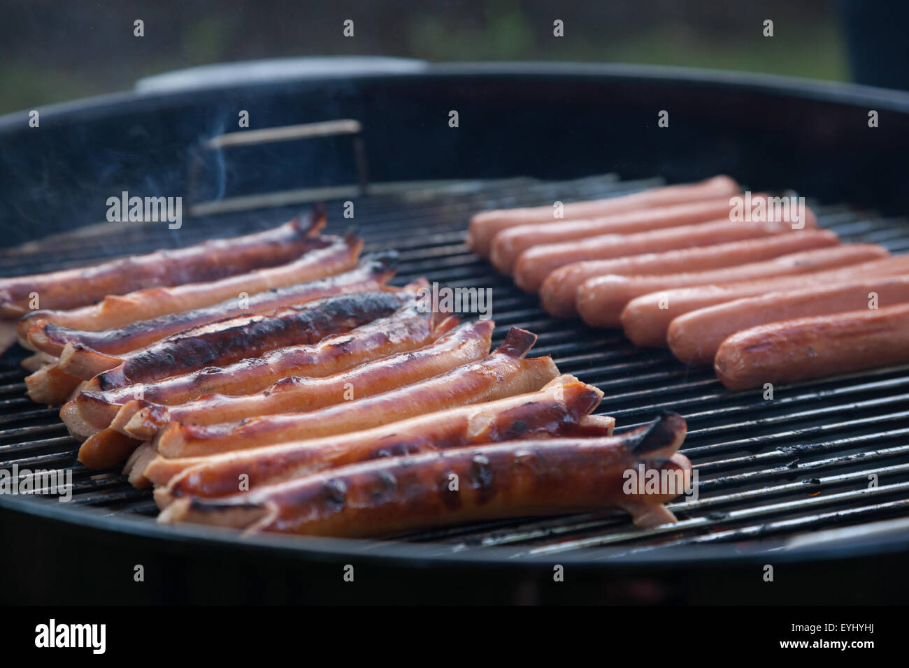 Plusieurs hot dog cuisson asseoir sur un grill au charbon de fumer Banque D'Images