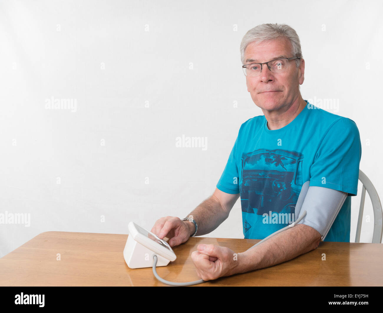 Homme d'âge moyen en prenant les mesures de pression à l'arrière-plan blanc vers la caméra Banque D'Images