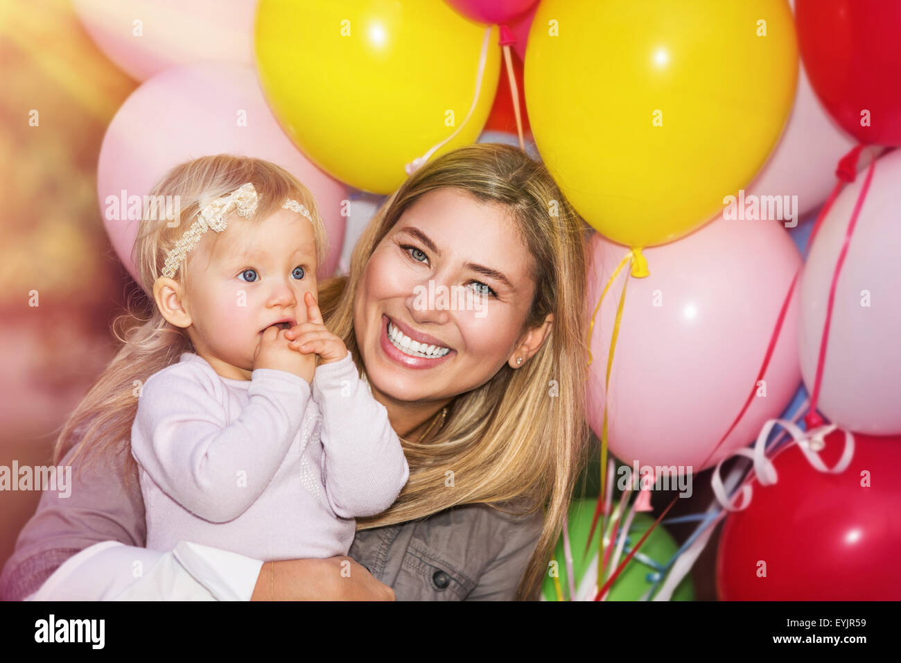 Anniversaire de baby girl, joyeux petit enfant avec la mère s'amuser en plein air avec de nombreux ballons colorés Banque D'Images