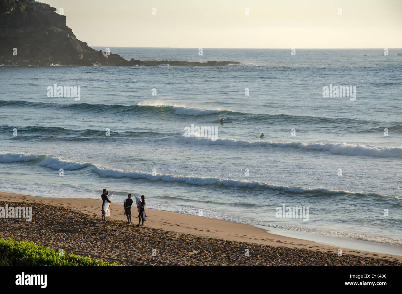 Les cavaliers de surf tiennent leurs planches et parlent sur la rive à Palm Beach, à Sydney, en Australie Banque D'Images