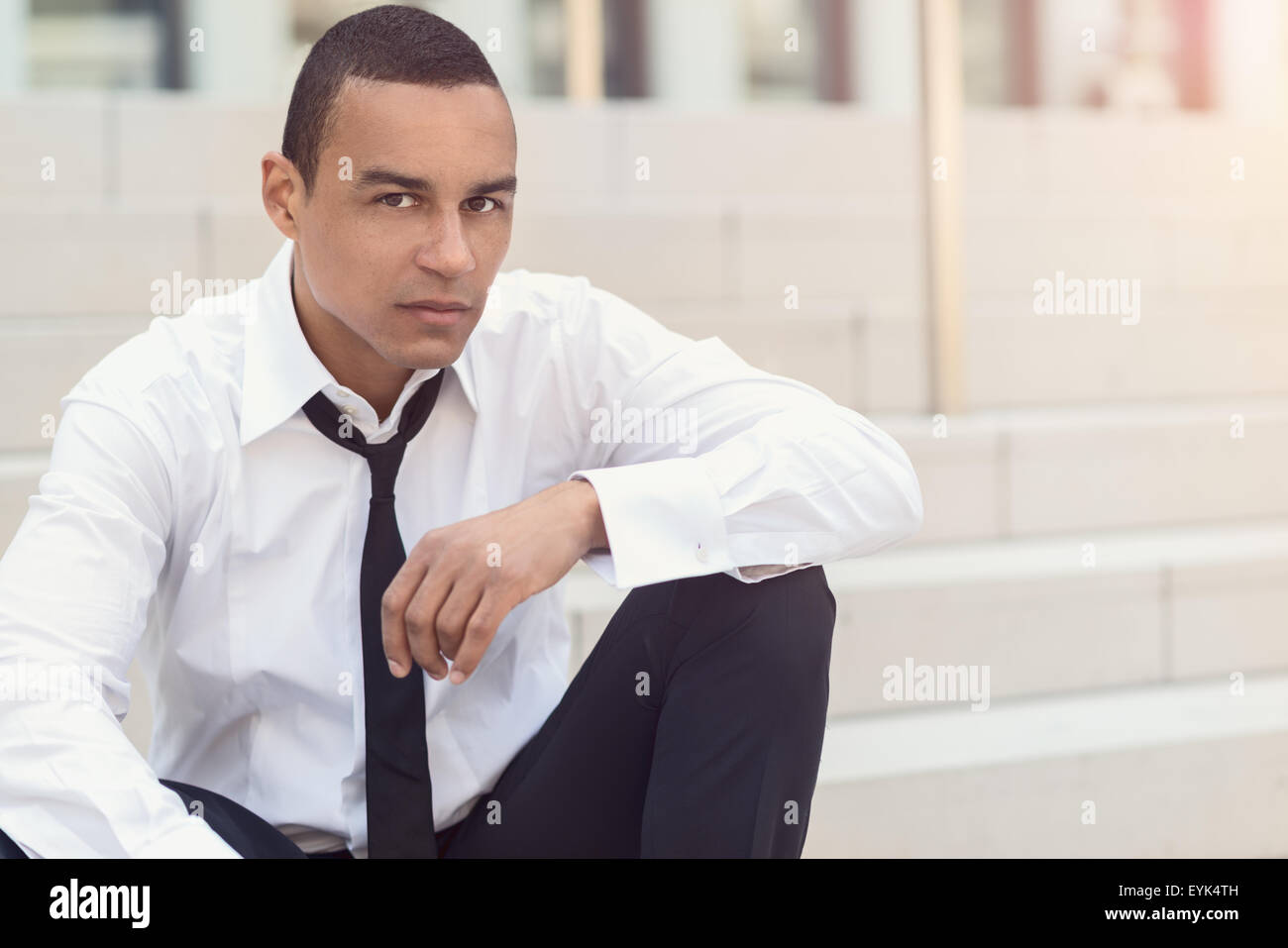 Homme d'affaires attrayant avec une cravate desserrée et déboutonna son col regardant la caméra, gros plan de la tête et des épaules Banque D'Images