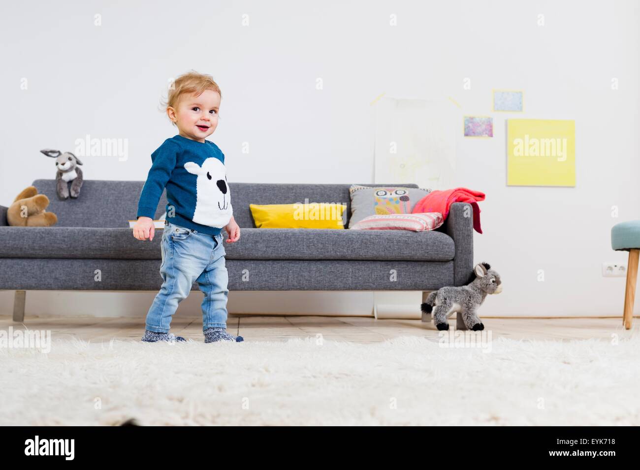 Garçon debout à côté de canapé à la maison Banque D'Images