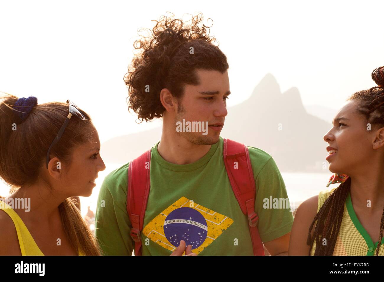 Trois jeunes amis adultes chat sur la plage d'Ipanema, Rio de Janeiro, Brésil Banque D'Images