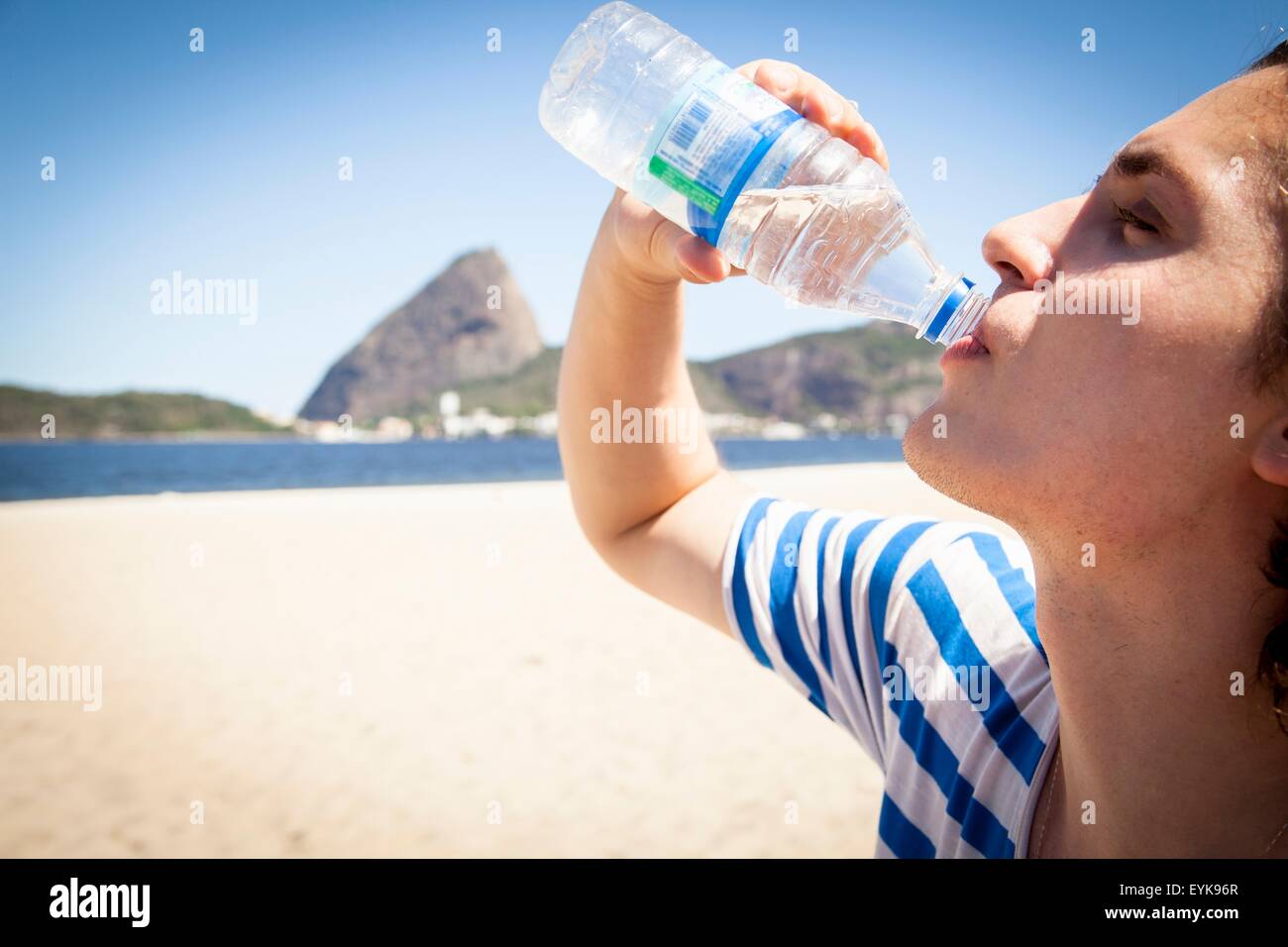 Jeune homme de boire une bouteille d'eau, à l'extérieur, close-up Banque D'Images