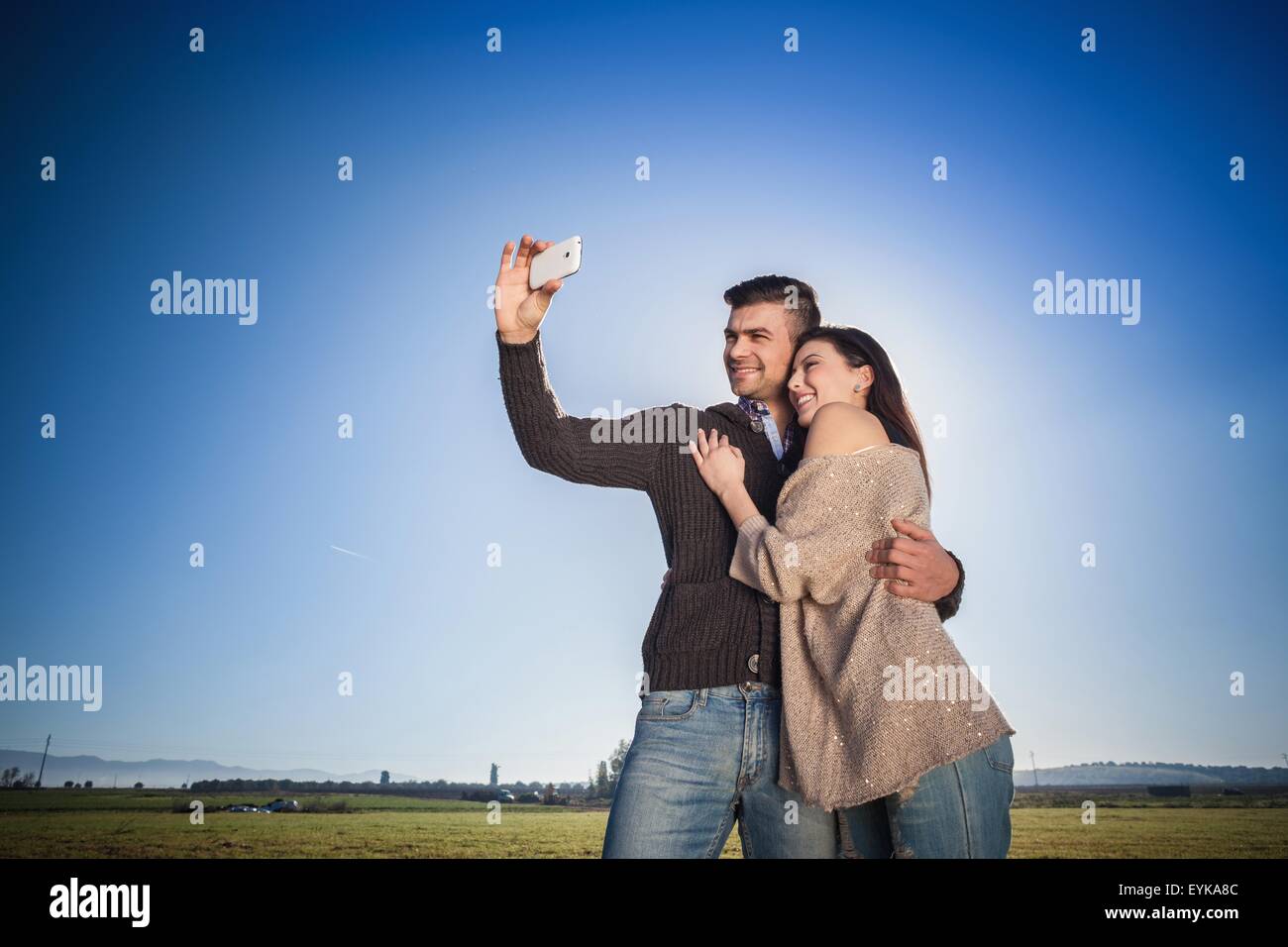Jeune couple photographing themselves against blue sky Banque D'Images