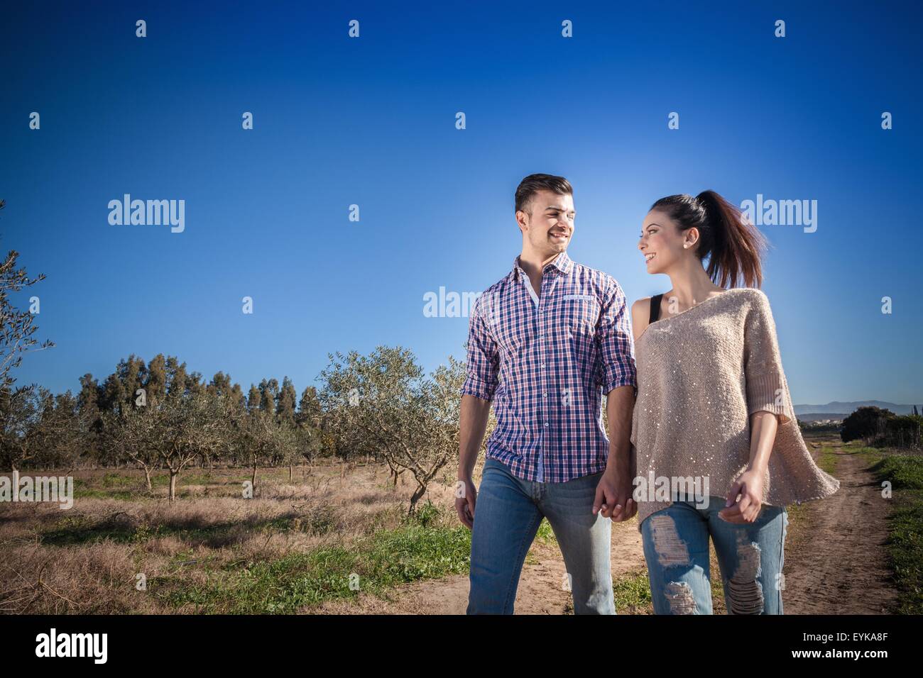 Young couple holding hands in field Banque D'Images