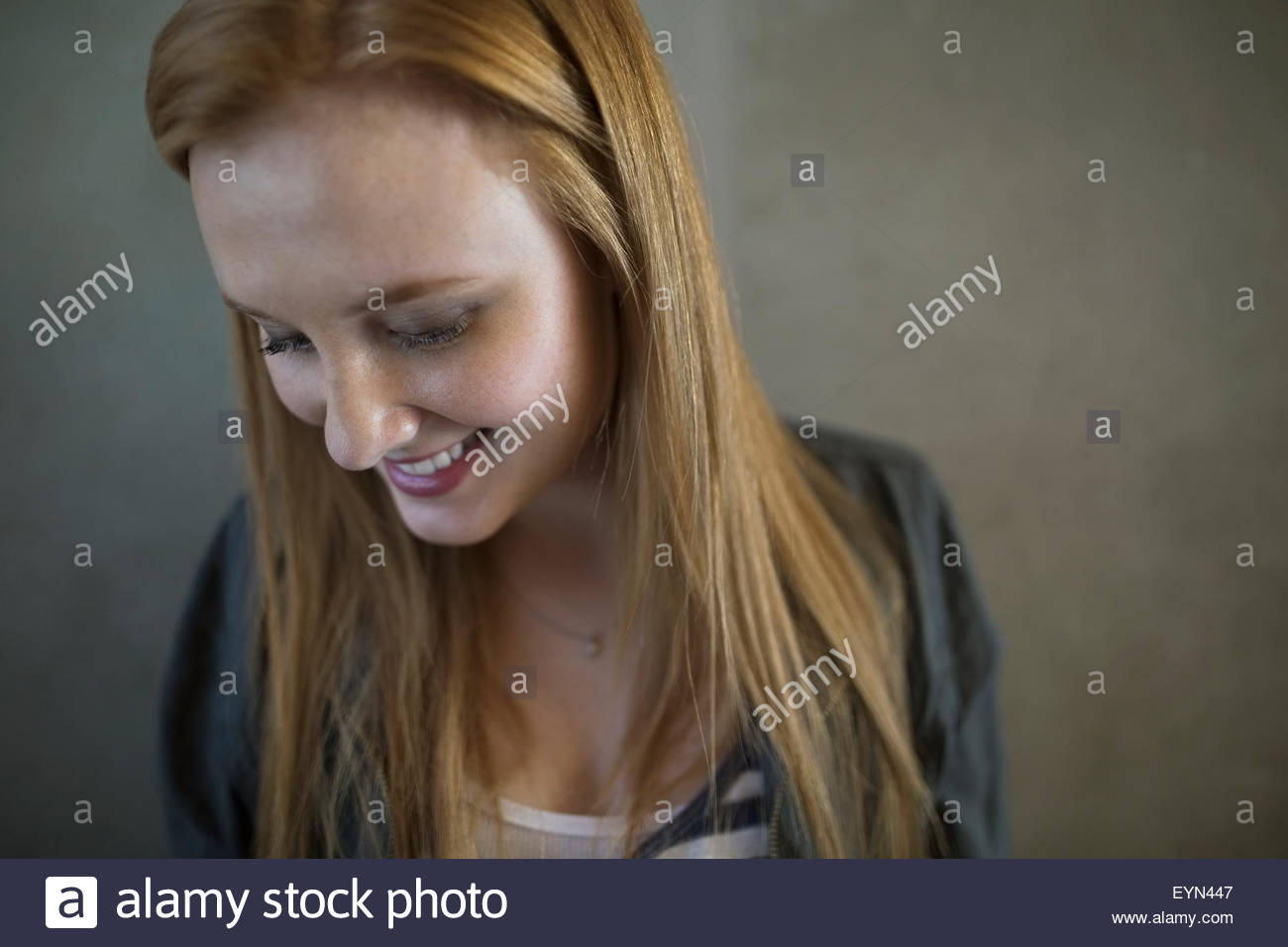 Portrait of smiling young woman red hair looking down Banque D'Images