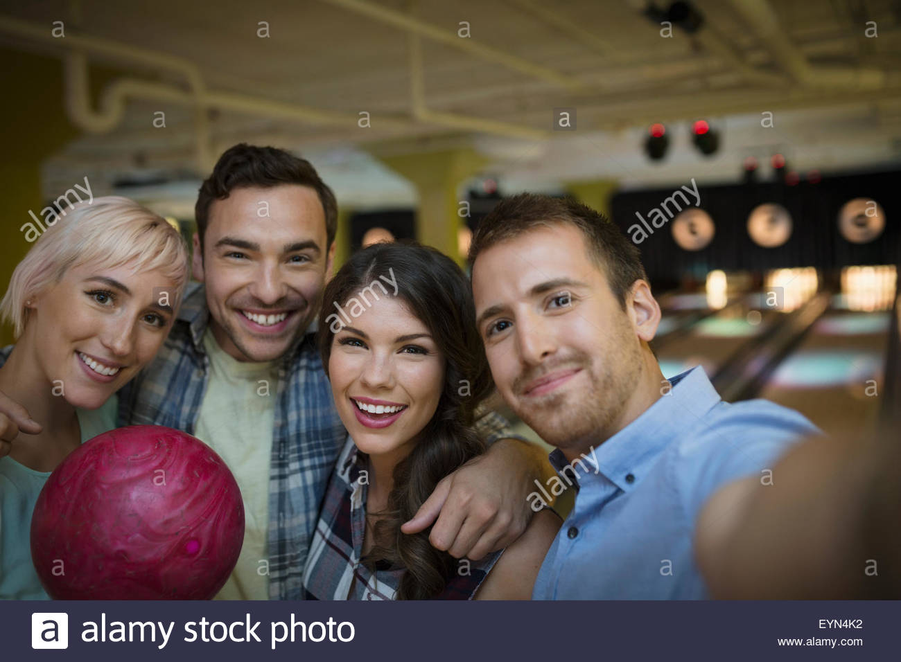 Portrait smiling friends hugging at bowling Banque D'Images
