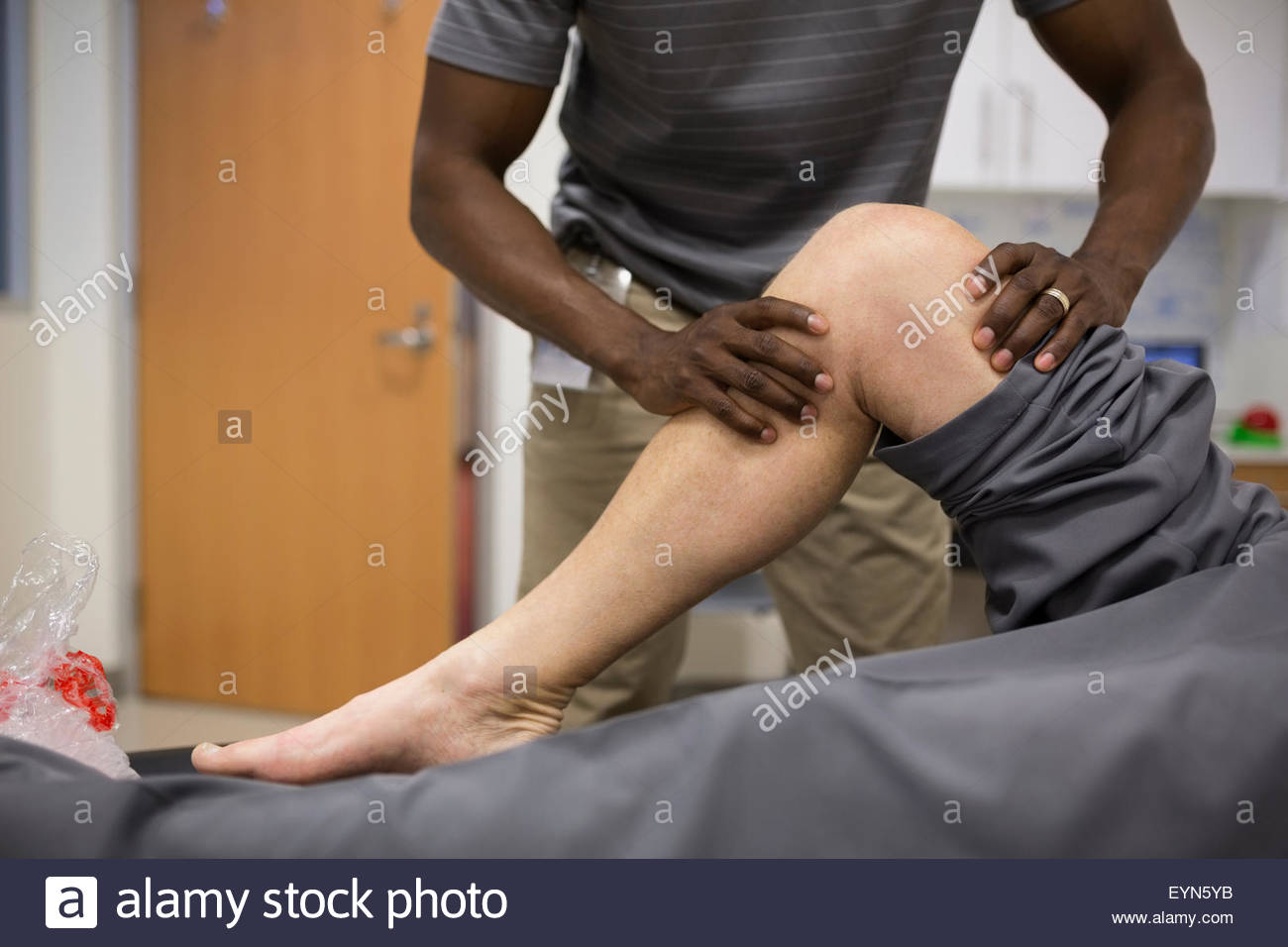 Thérapeute physique s'étendant du genou du patient Banque D'Images