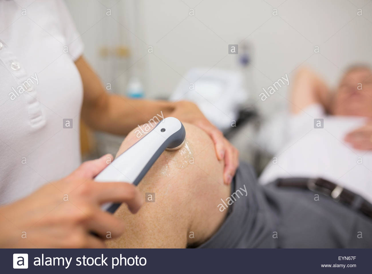 Thérapeute physique l'utilisation d'un capteur sur le genou du patient Banque D'Images