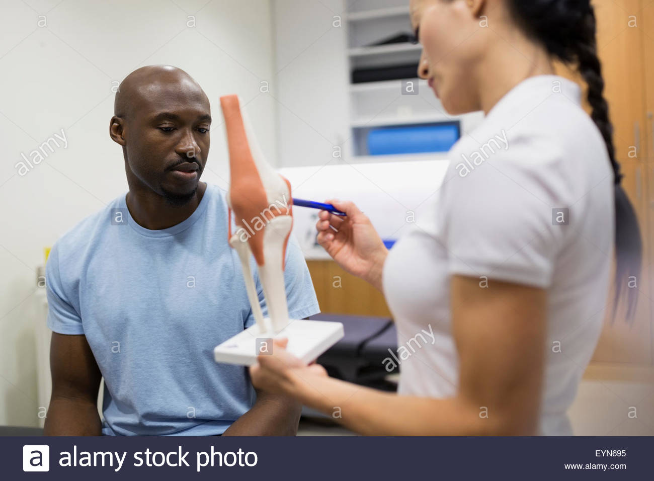 Thérapeute physique expliquant au patient modèle du genou Banque D'Images