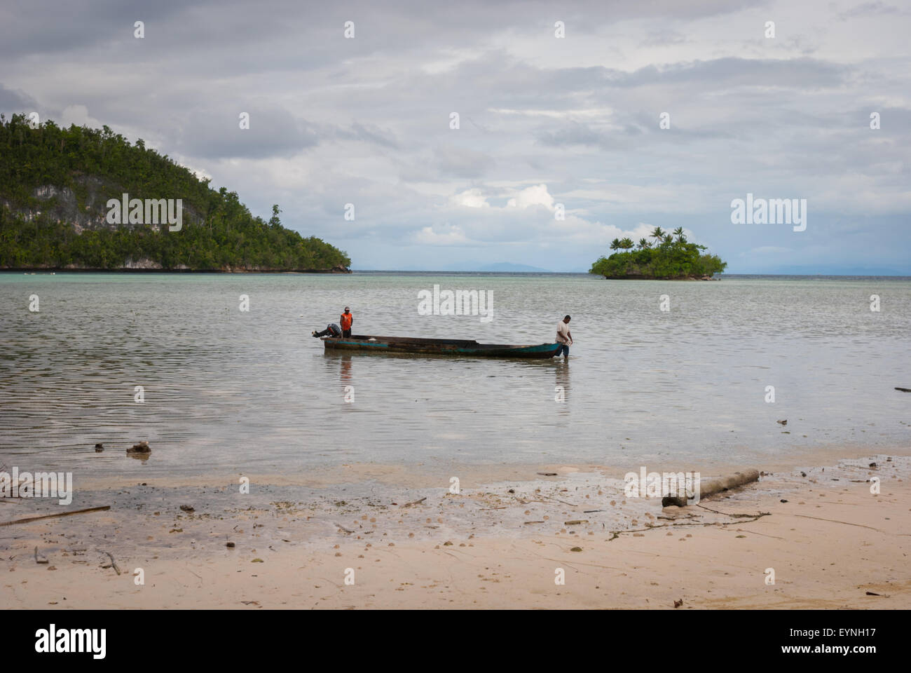 Pêcheurs et canoë en bois sur les eaux peu profondes près de l'île Friwen, une petite île située dans la zone marine protégée du détroit de Dampier. Banque D'Images