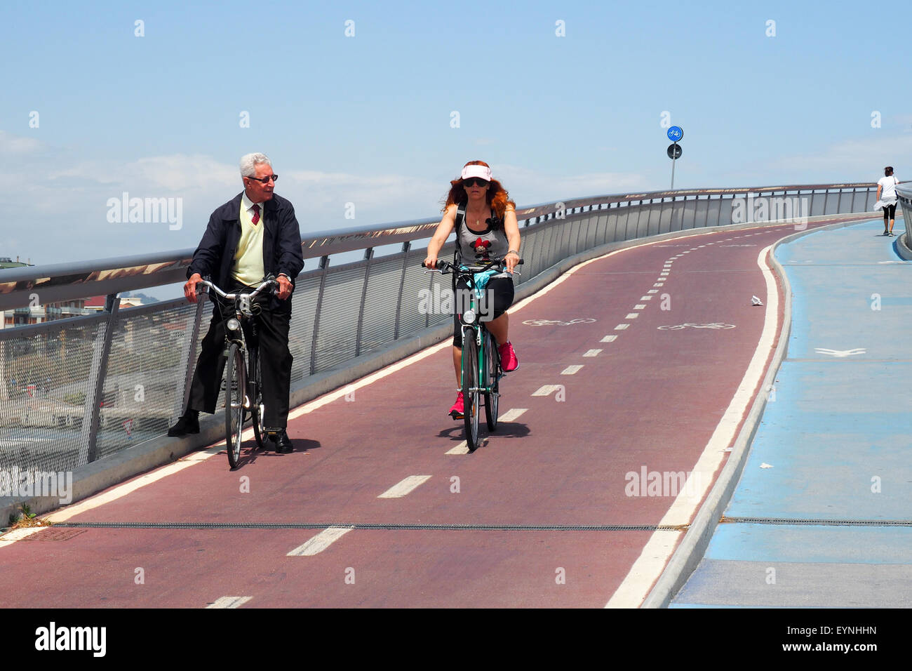 Deux cyclistes et un piéton sur un cycle-pont suspendu pour piétons. Banque D'Images