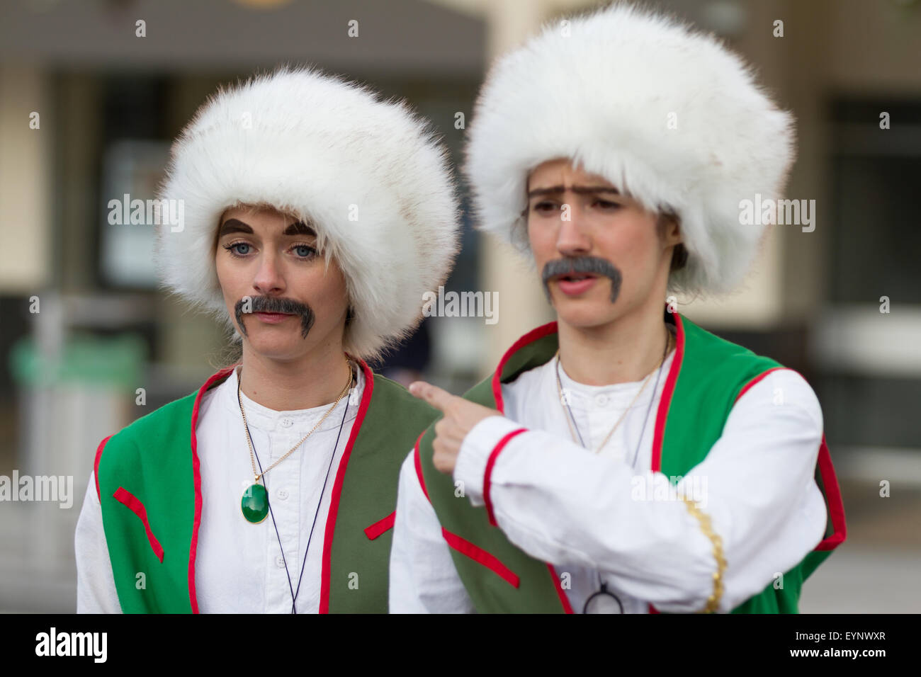 Stockton-on-Tees, UK, samedi, 01 août, 2015. Deux artistes de rue féminin comédie habillés comme des hommes, en fancy dress costumes folkloriques, avec de faux sourcils et moustaches fausses, à l'instant de lumière, la 28e Stockton International Riverside Festival. Banque D'Images