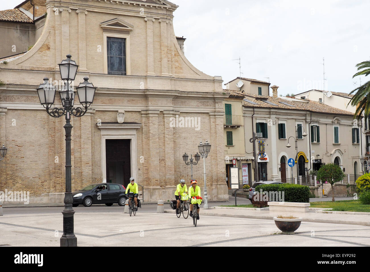 Trois des cyclotouristes équitation leurs vélos à travers la Piazza Gabriele Rossetti, Vasto. Banque D'Images