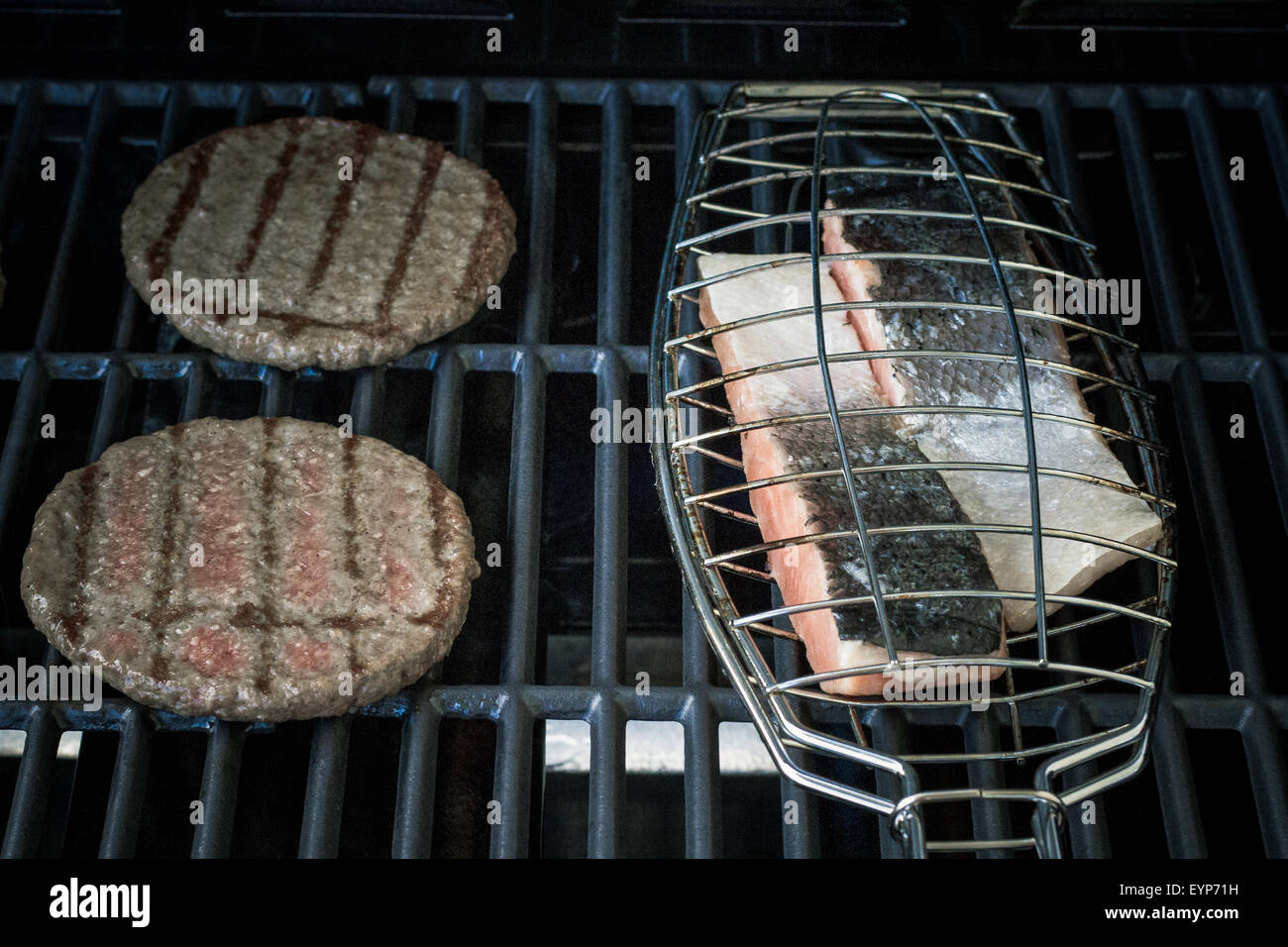 Deux tranches de hamburger et pavé de saumon sur le gril, soft focus Banque D'Images