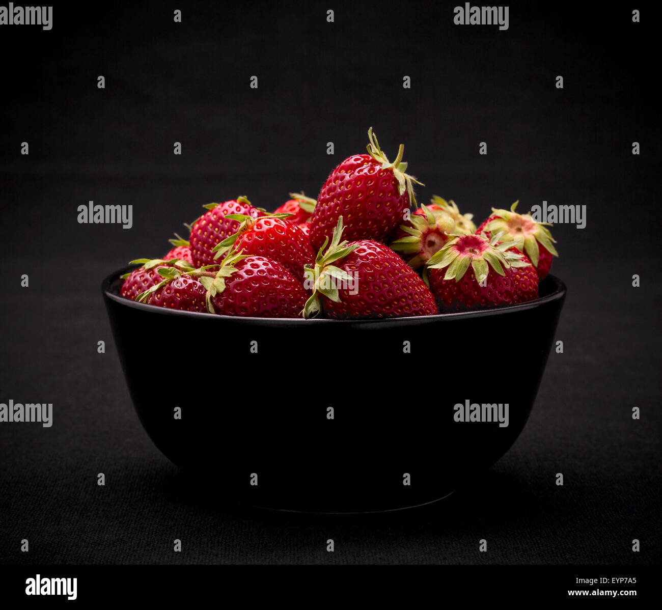 Dans un bol de fraises fraîches mûres sur fond noir, Close up Banque D'Images