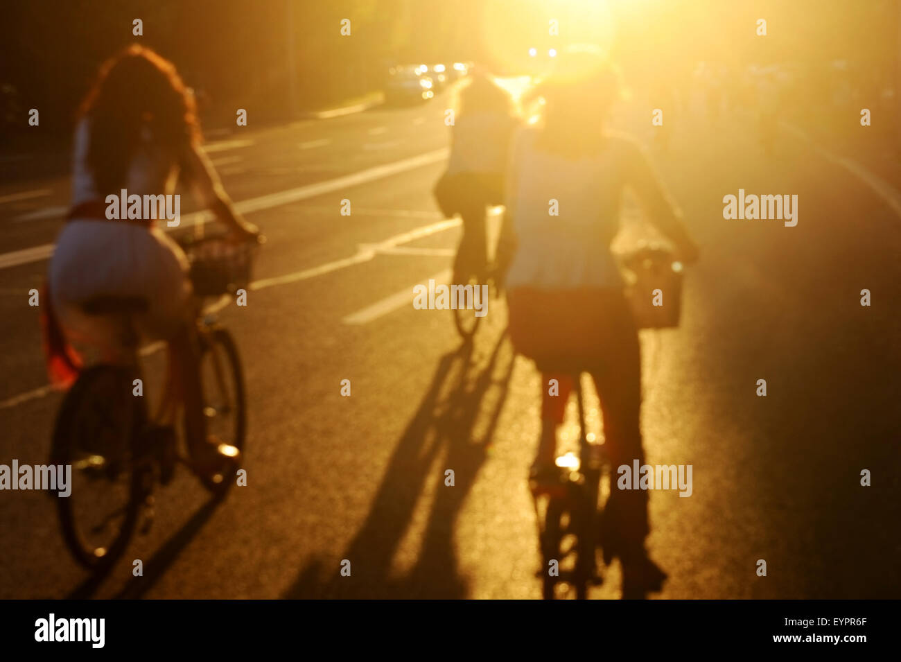Photo floue de la femme sur les bicyclettes équitation dans la ville au coucher du soleil dans la belle lumière Banque D'Images