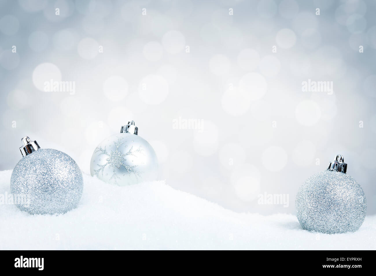Boules de Noël argent sur la neige avec des lumières blanches et de l'argent flou artistique en arrière-plan. Profondeur de champ. Banque D'Images