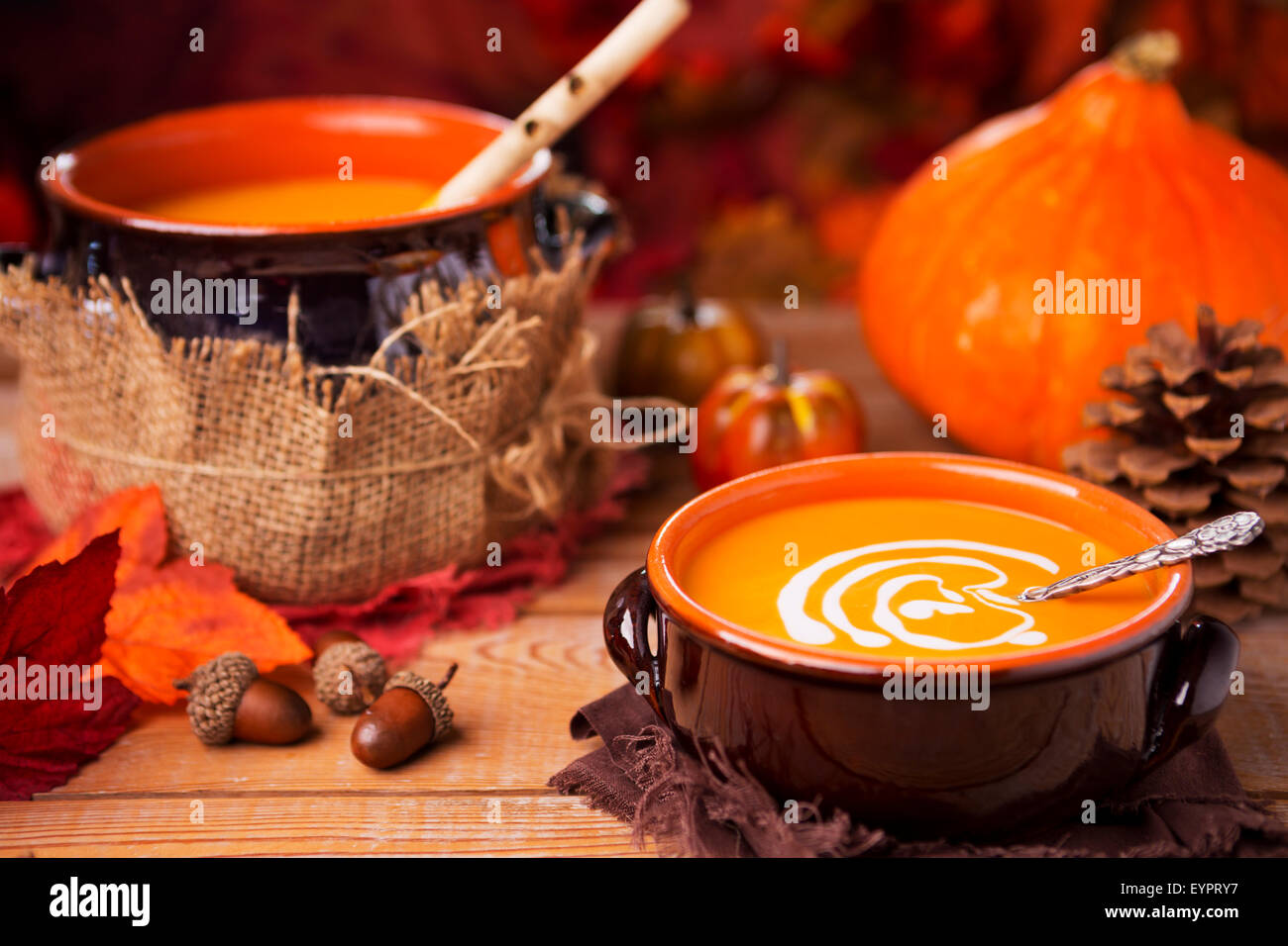 Un bol de soupe au potiron crémeuse faite maison sur une table rustique avec des décorations d'automne. Banque D'Images