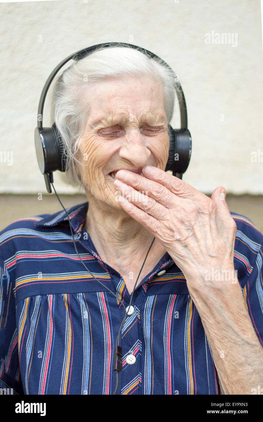 Quatre-vingt-dix ans de réaction de grand-mère lors de l'écoute de la musique moderne. Grand-mère listening to music on headphones Banque D'Images
