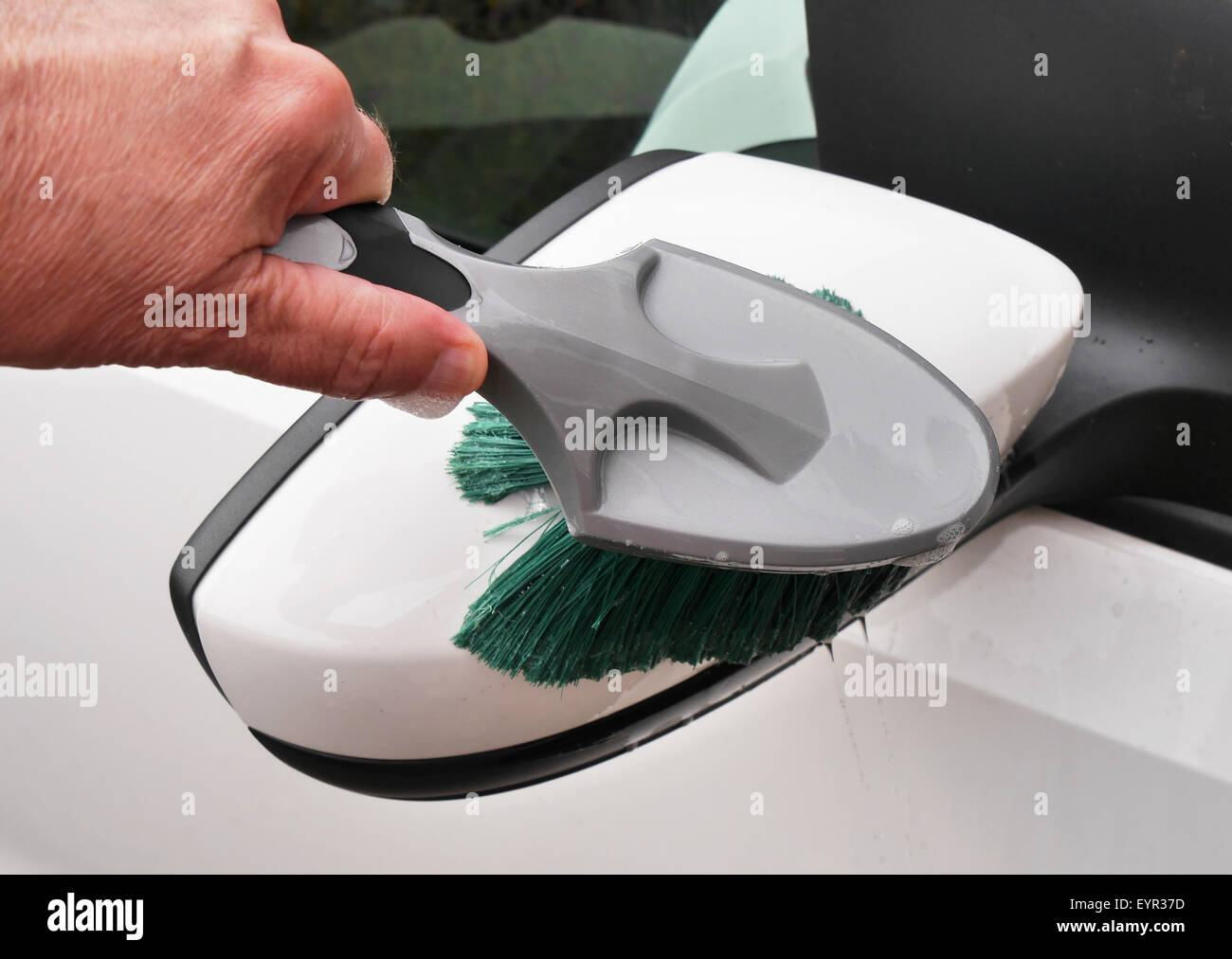 Man holding brosse pour nettoyer un miroir de voiture Banque D'Images