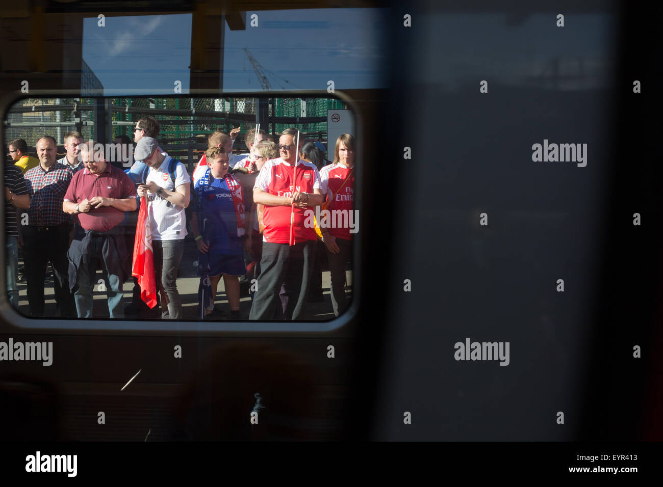 Les supporters de football sur une plate-forme du train en attente, vu à travers une fenêtre de train Banque D'Images