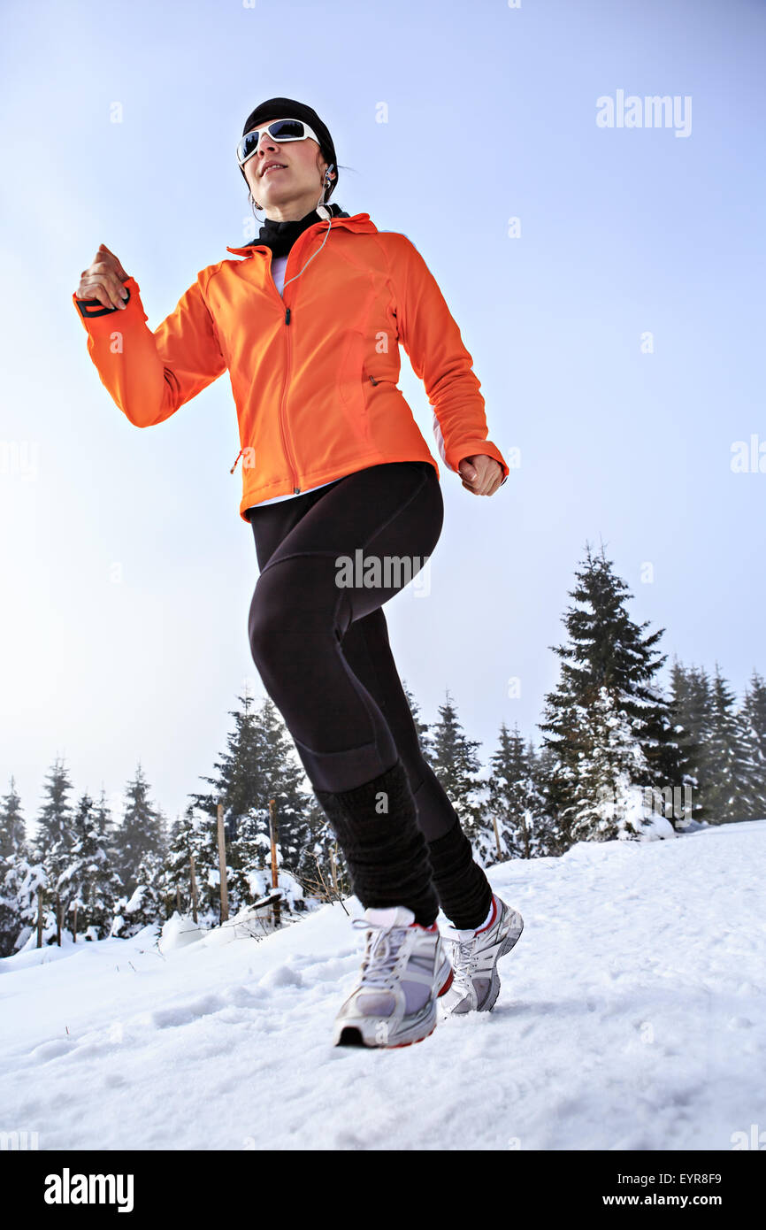 Une jeune femme le jogging dans la forêt d'hiver Banque D'Images