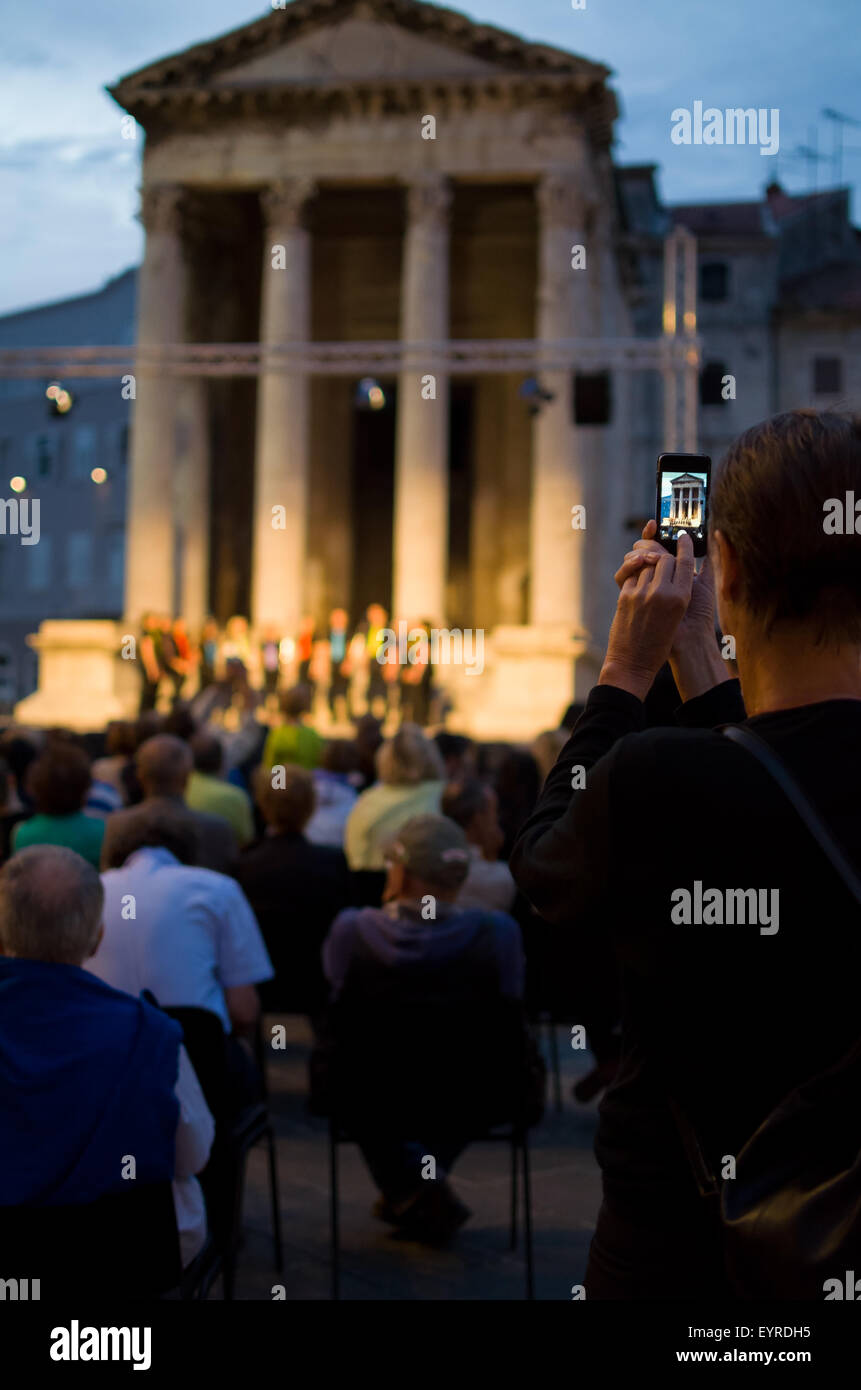 La prise d'un snapshot de tourisme avec le Smartphone d'un programme culturel en soirée à la verticale Banque D'Images