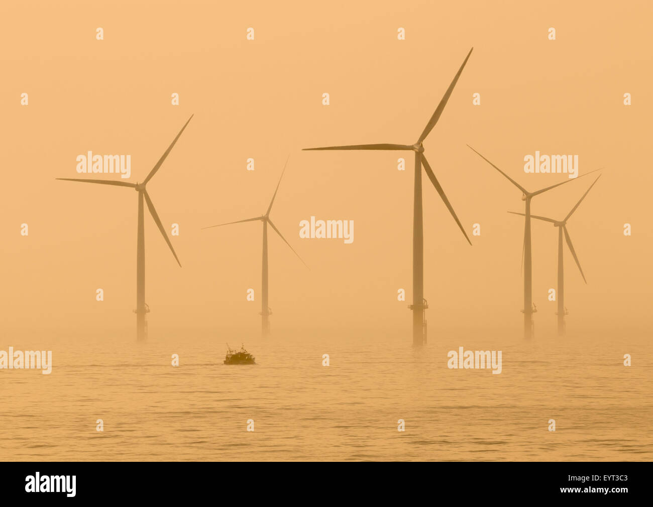 Bateau de pêche près de Parc éolien en mer de Teesside sur la côte nord-est près de Redcar au lever du soleil. Angleterre, Royaume-Uni Banque D'Images