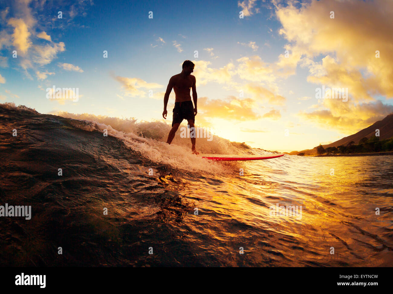 Le surf au coucher du soleil. Jeune homme équitation vague au coucher du soleil. Mode de vie actif en plein air. Banque D'Images