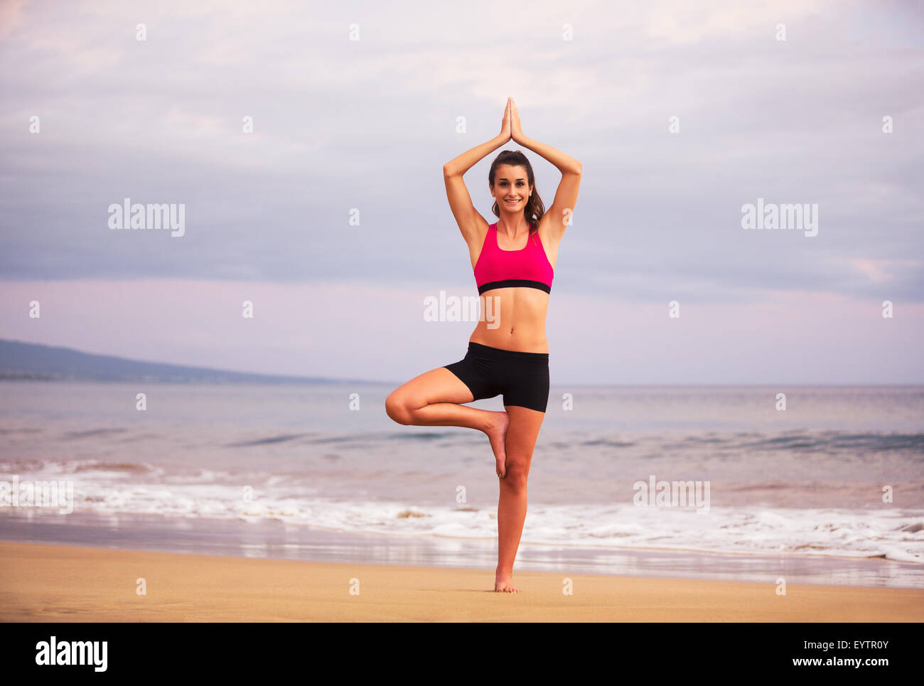 Jeune femme en bonne santé pratiquant le yoga sur la plage au coucher du soleil. Mode de vie sain et actif. Banque D'Images