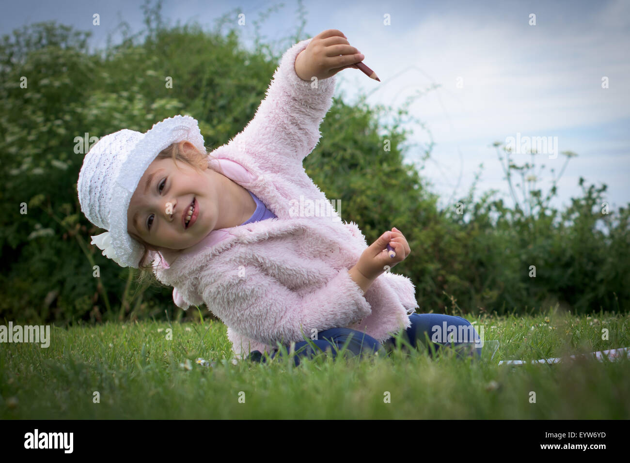 Petite fille assise sur l'herbe Banque D'Images