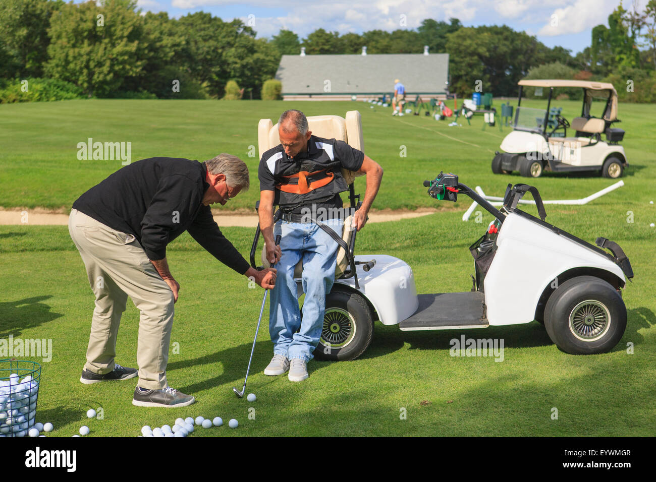 Homme avec une lésion de la moelle épinière dans un panier au putting-green de golf avec un instructeur Banque D'Images