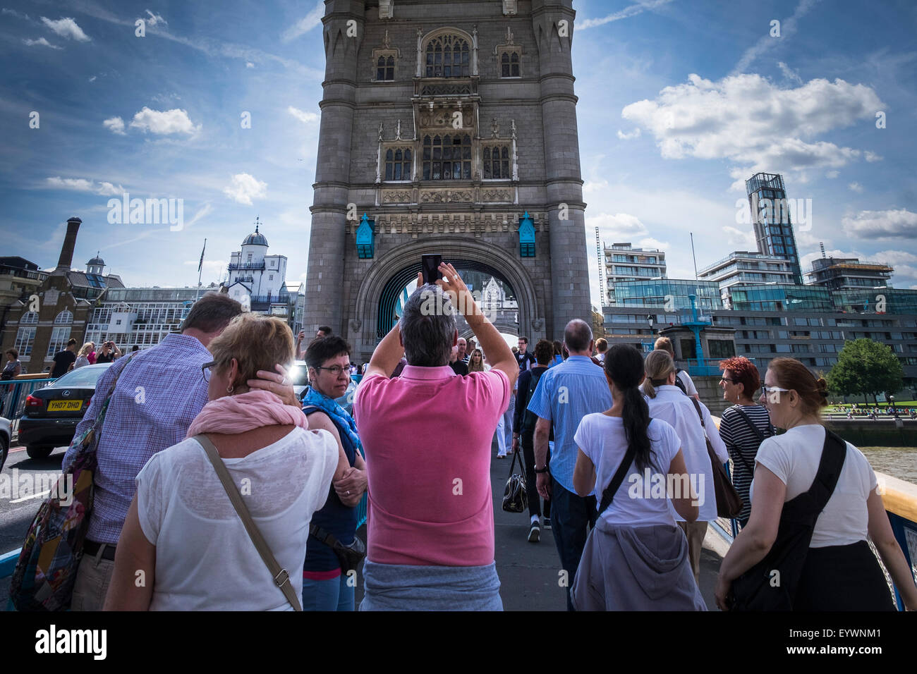 Un touriste en utilisant son téléphone portable pour photographier le Tower Bridge à Londres. Banque D'Images