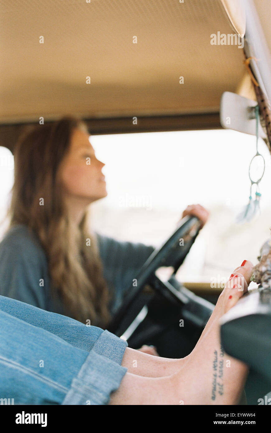 Femme aux pieds nus reposant ses pieds sur le tableau de bord d'un 4x4, un tatouage sur son pied droit, une autre femme au volant. Banque D'Images