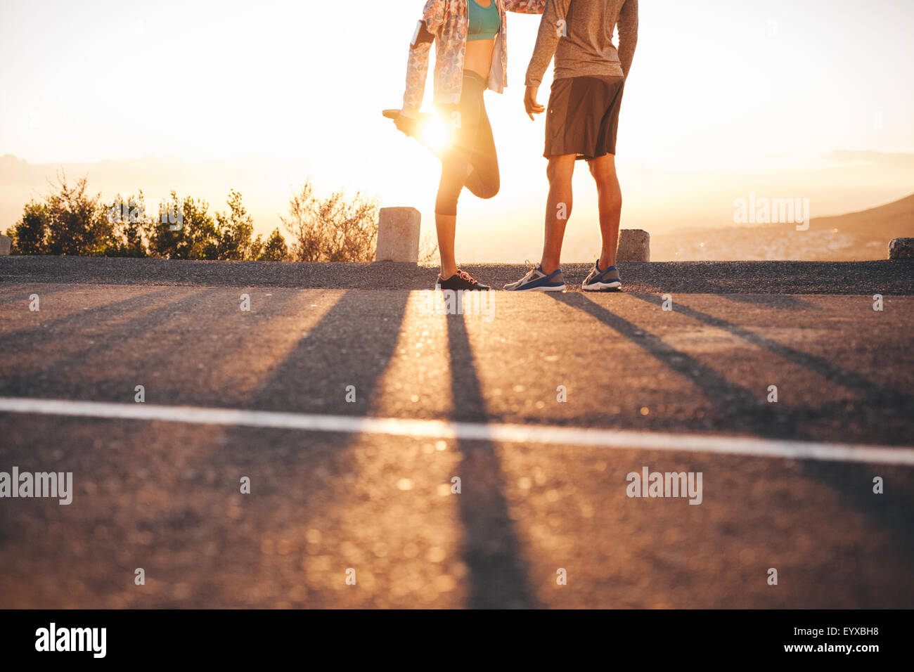 Cropped shot de fit jeune couple l'échauffement avant une course ensemble au lever du soleil. Jeune homme et femme exerçant en matinée. Banque D'Images