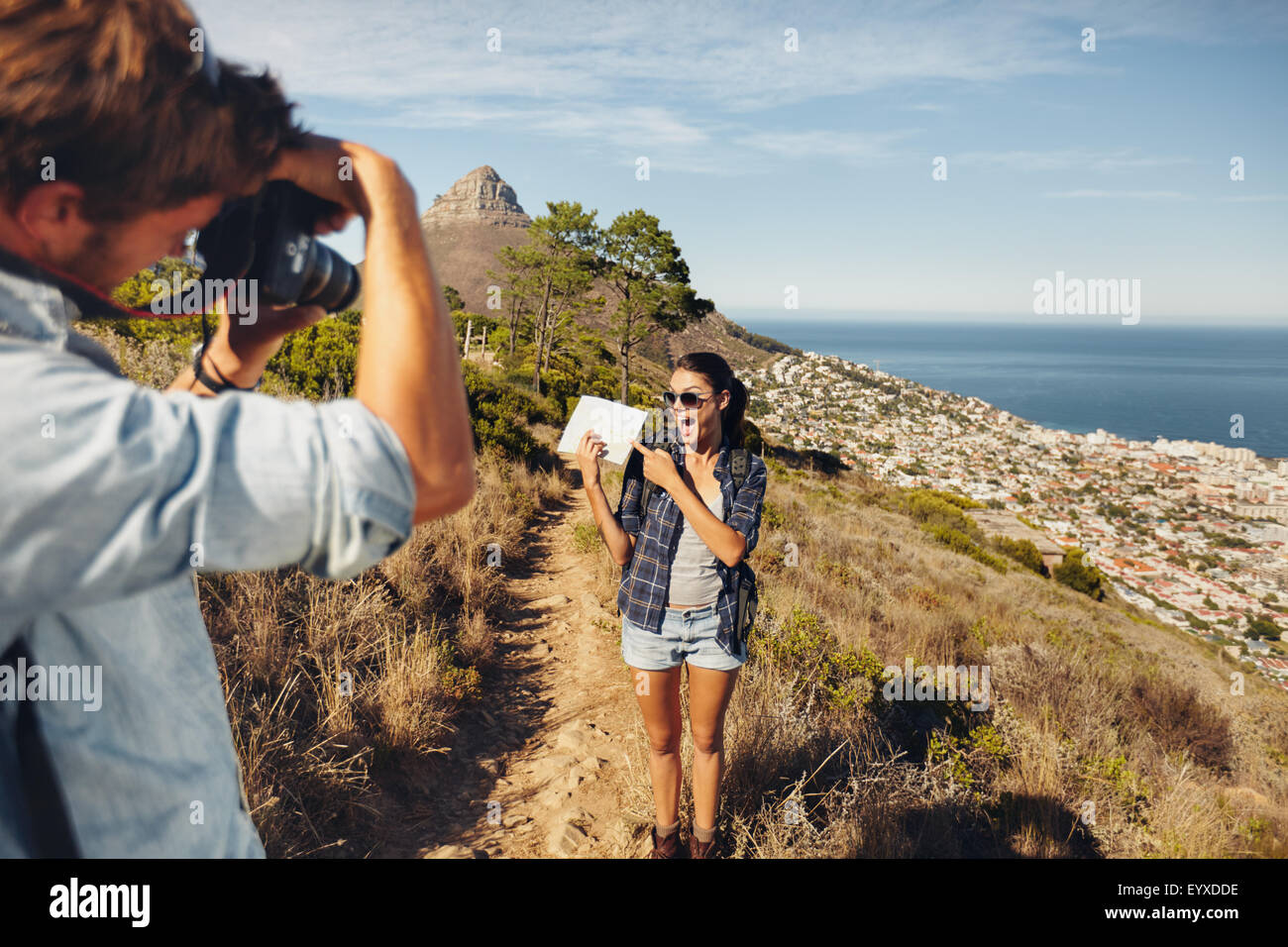 Excitée jeune femme montrant la carte et se faisant passer pour son petit ami en tenant ses images avec un appareil photo numérique. Jeune couple hiking on moun Banque D'Images