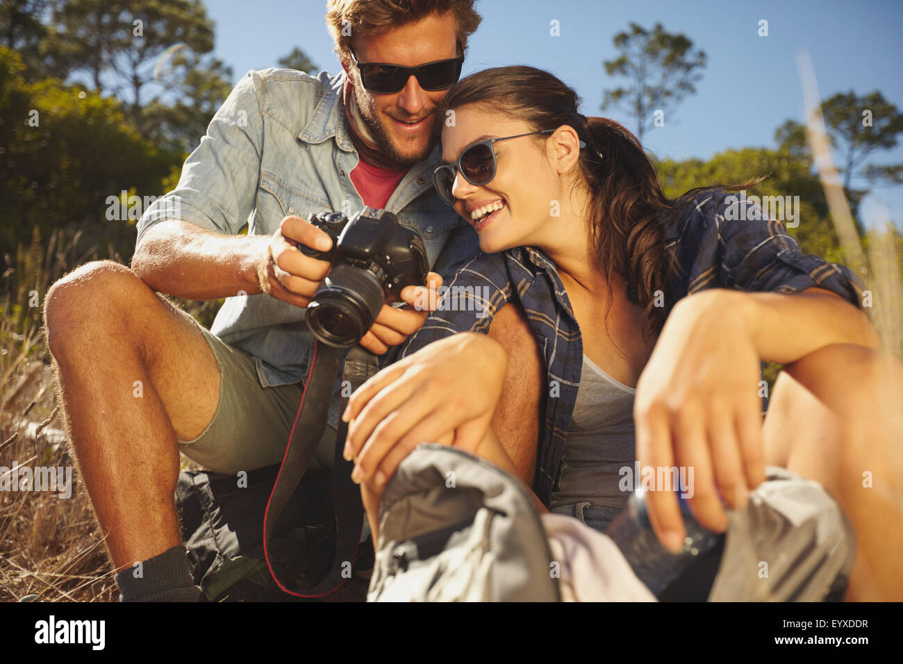 Couple randonneur à la photo prise sur l'appareil photo numérique au cours de voyage en vacances en plein air. Smiling couple Taking a break on a hike Banque D'Images