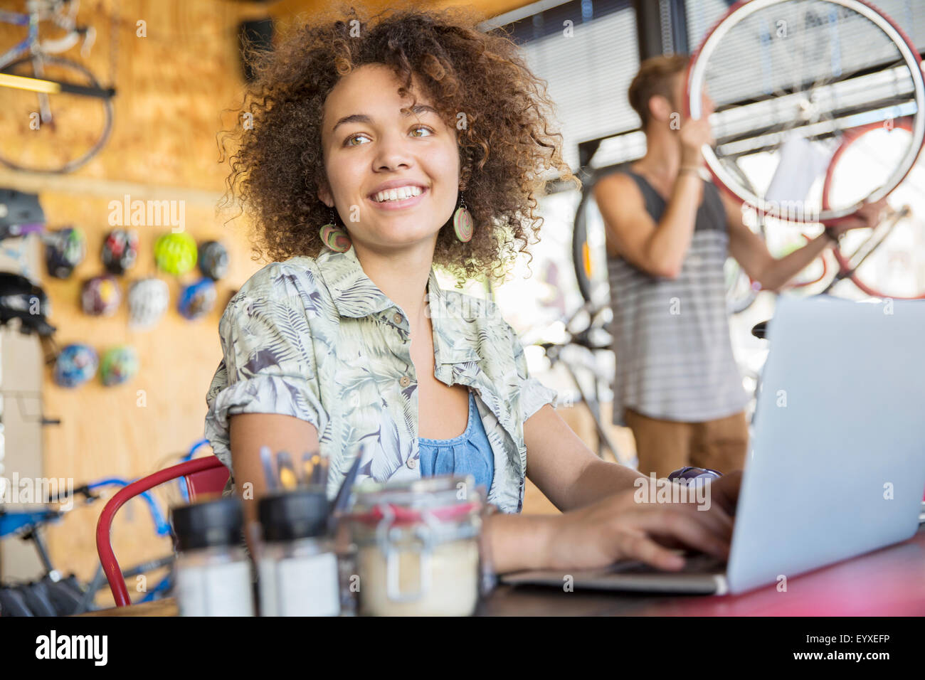 Smiling woman working at laptop in Bicycle shop Banque D'Images
