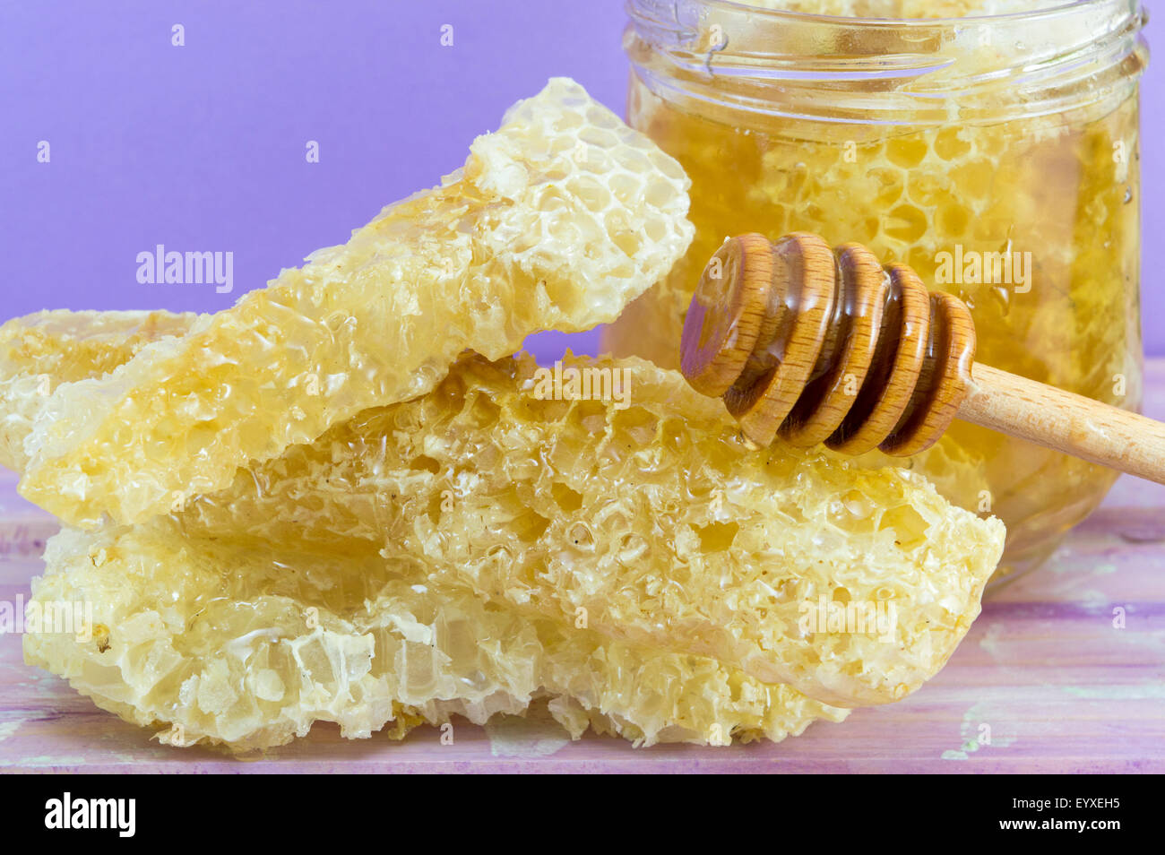 Balancier d'abeilles et pot de miel sur fond violet Banque D'Images