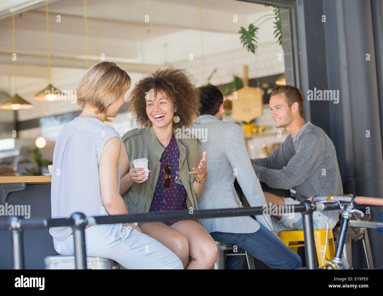 Laughing friends hanging out boire du café sur patio cafe Banque D'Images