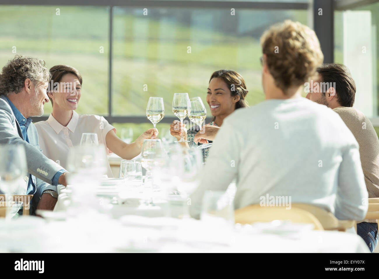Friends toasting wine glasses in restaurant ensoleillé Banque D'Images