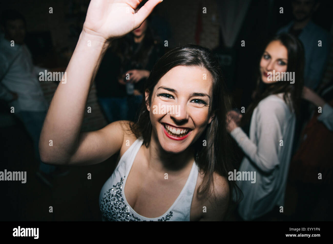 Smiling woman waving in nightclub Banque D'Images