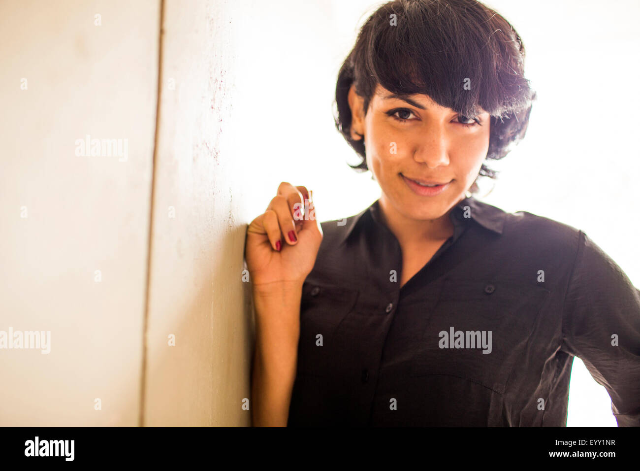 Smiling young woman leaning on wall Banque D'Images